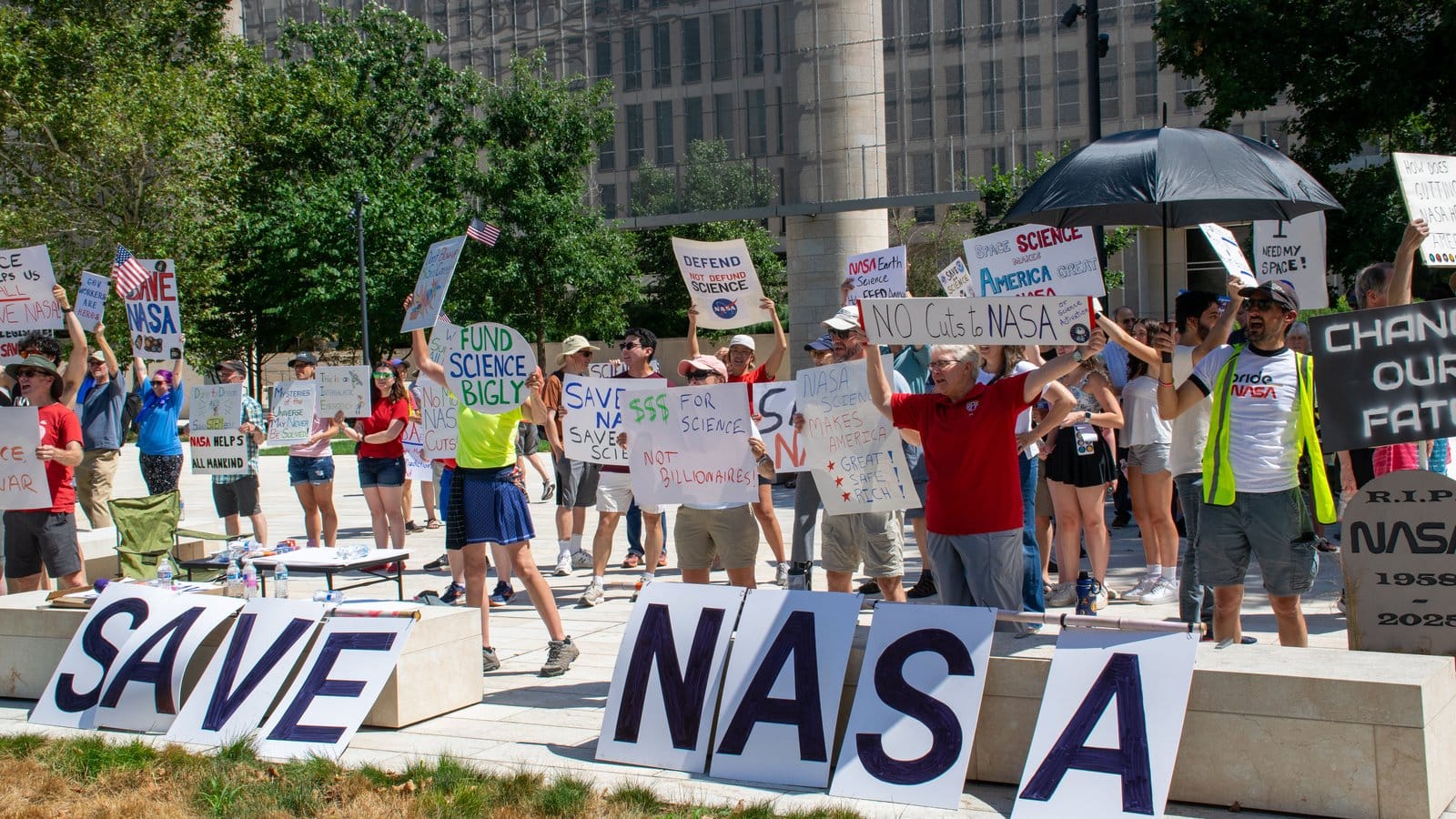 holistic health People hold signs outside on a sunny day in protest of NASA budget cuts, July 20, 2025.